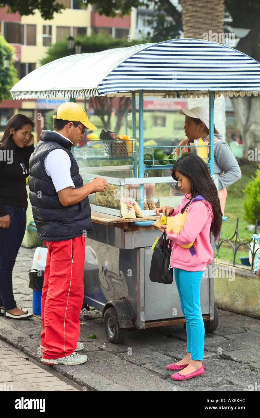 BANOS, ECUADOR - FEBRUARY 22, 2014: Unidentified people eating at snack stand selling roasted pork skin with beans (mote), tomato, onion and corn Stock Photo