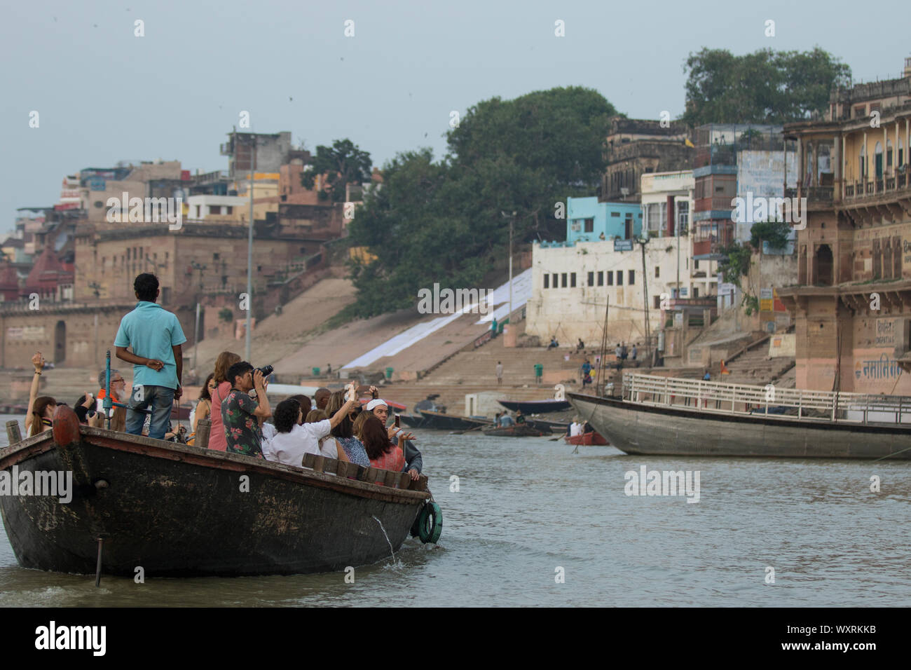 International tourists taking boat ride on Ganges river at Varanasi to experience the beauty of this city. Stock Photo