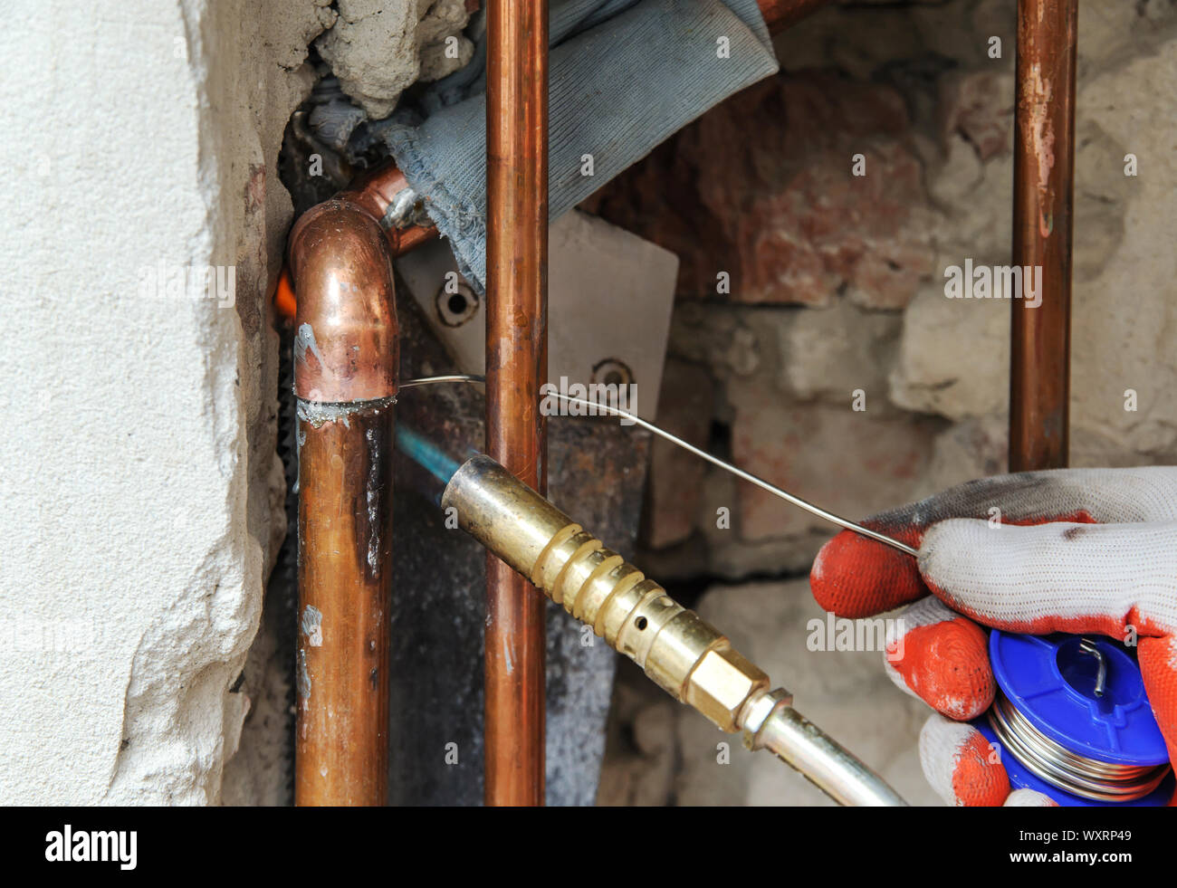 A worker is using the gas burner and the solder for soldering copper