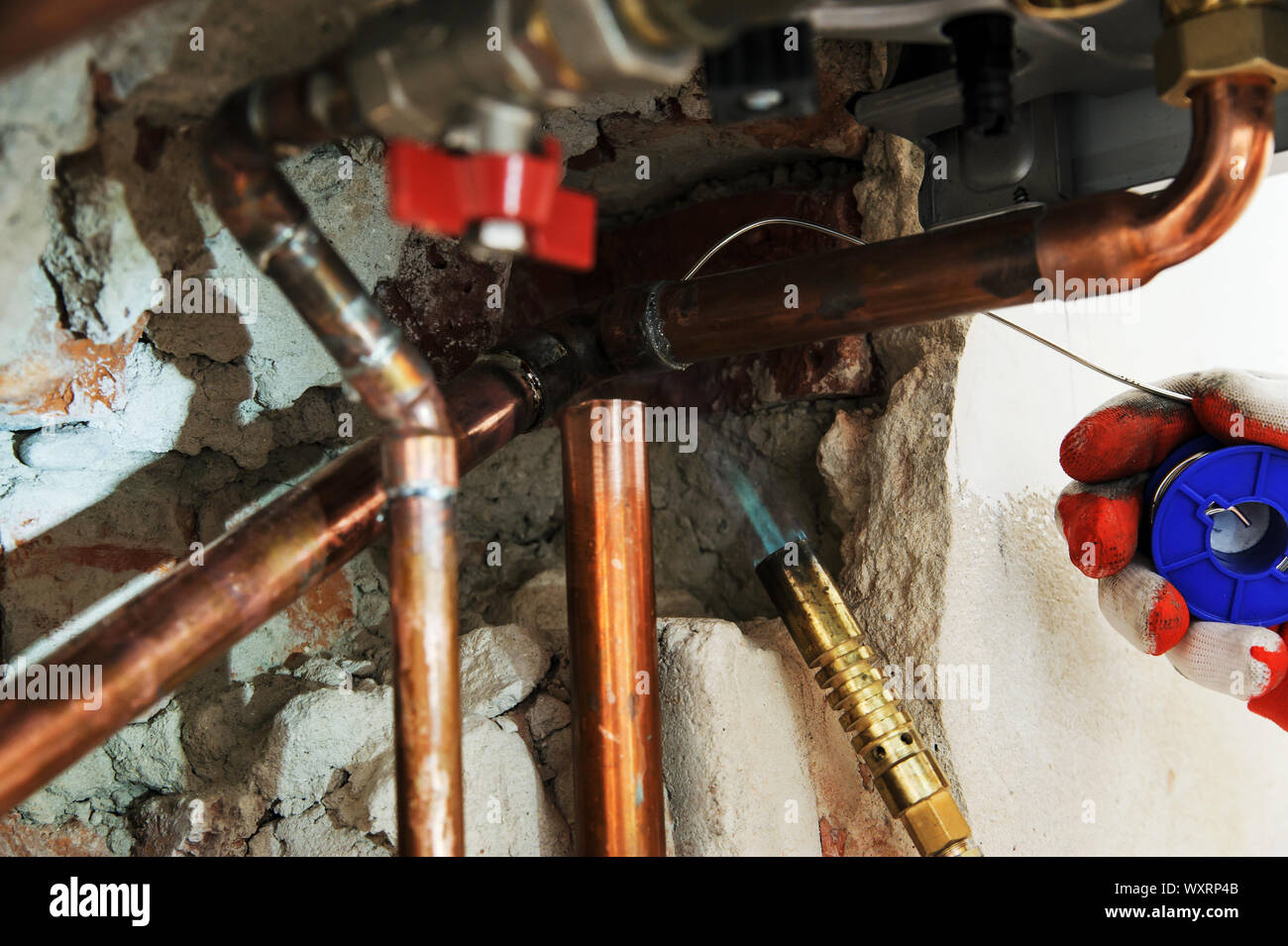 A worker is using the gas burner and the solder for soldering copper