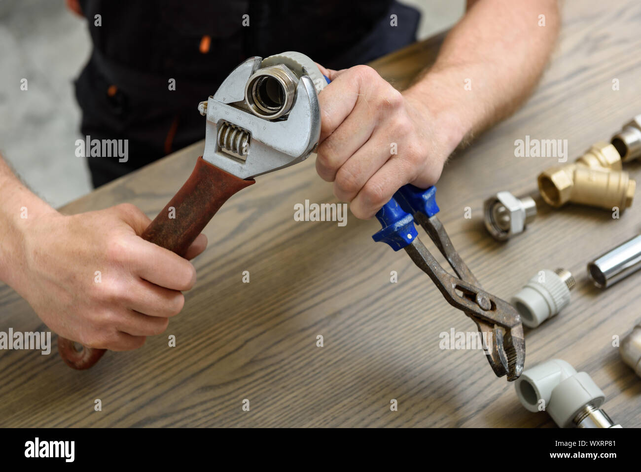 A worker is connecting elements of the plumbing with the adjustable wrenches. Stock Photo