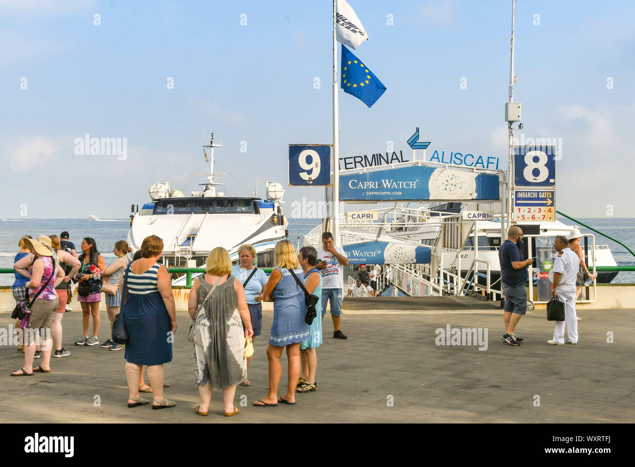 SORRENTO, ITALY - AUGUST 2019: People waiting to board a fast ferry from Sorrento to the Isle of Capri. Two ferries are docked in the background Stock Photo