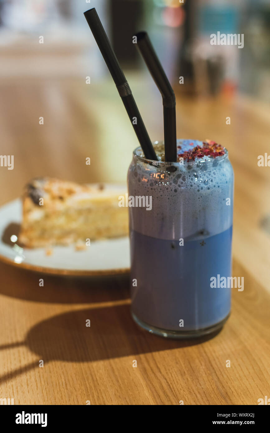 A drink from blue matches in a coffee shop. Healthy and proper expensive Chinese tea with a slice of cake on a wooden table. Lifestyle photo. Stock Photo