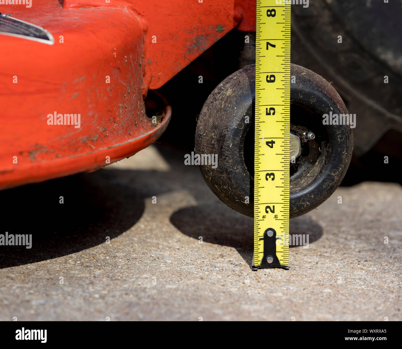 Lawn mower deck and anti-scalp gauge wheel with tape measure checking height adjustment. lawn equipment maintenance and repair  concept Stock Photo