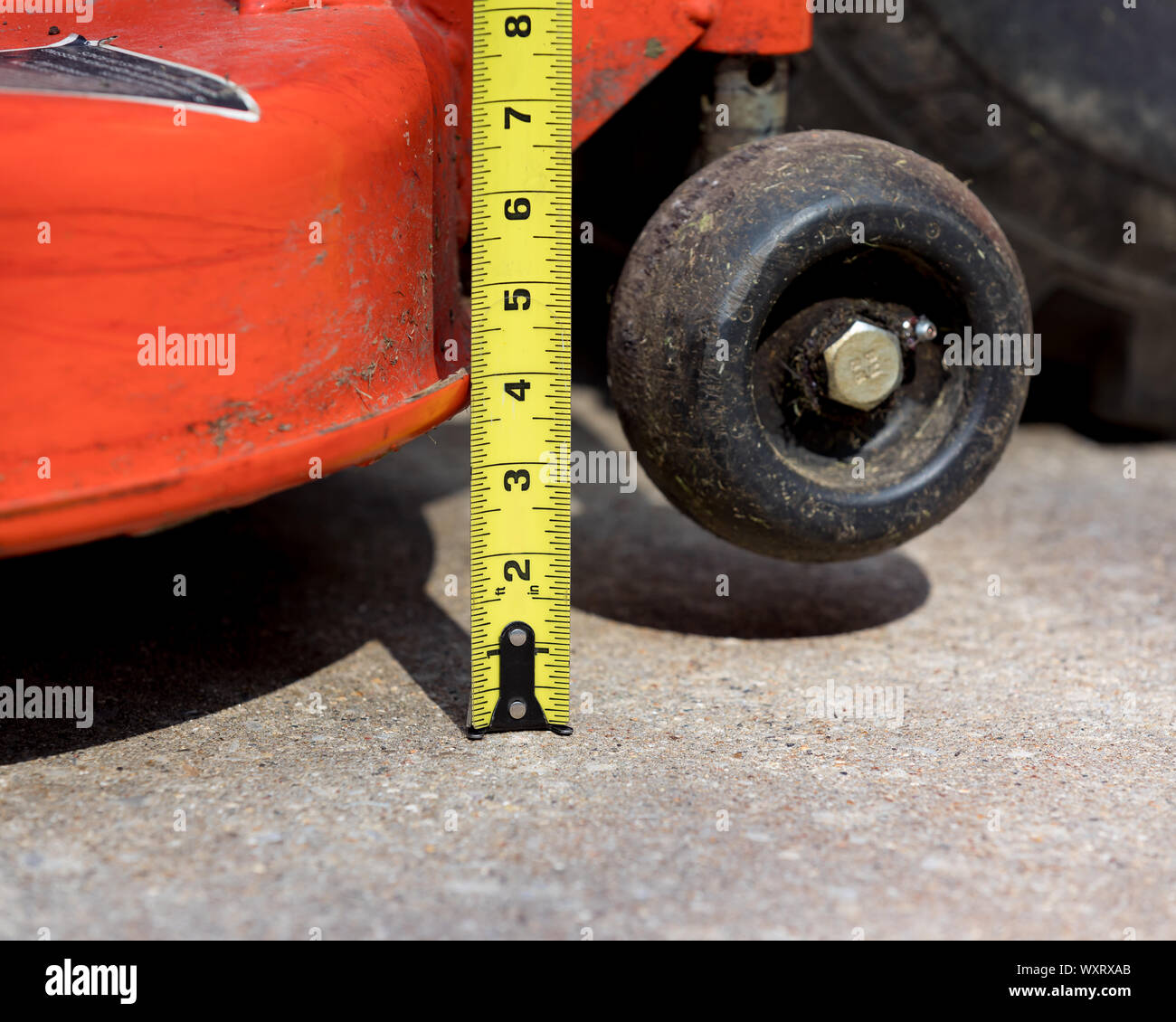 Lawn mower deck and anti-scalp gauge wheel with tape measure checking height adjustment. lawn equipment maintenance and repair  concept Stock Photo