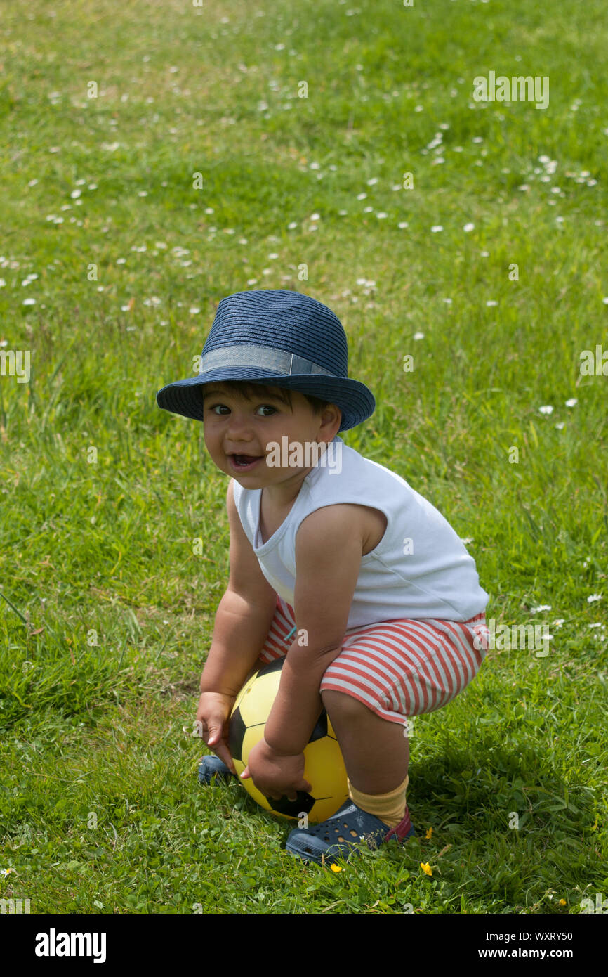Cute toddler in hat sitting on ball Stock Photo