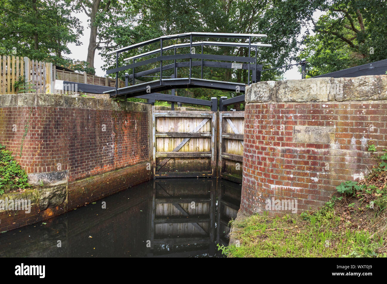Typical pound lock with brick walls and wooden gates on the Basingstoke Canal and towpath, Knaphill, Woking, Surrey, southeast England, UK Stock Photo