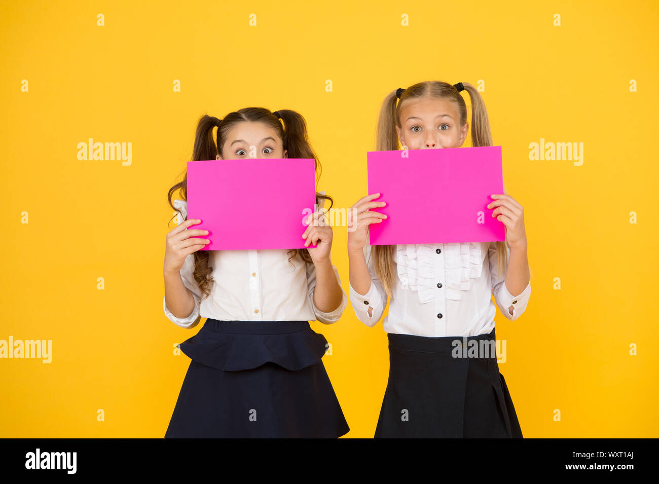 Drawing attention. Happy kids holding empty sheets of paper. Little kids smiling with pink drawing papers. Small kids smiling with blank advertisement posters. Cute kids advertising, copy space. Stock Photo