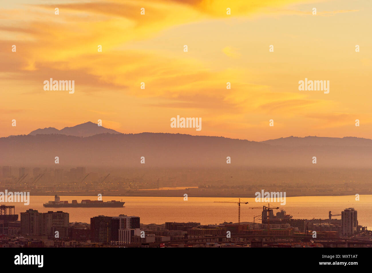 A cargo ship at sunrise moves out from the port of Oakland in the San Francisco Bay Stock Photo