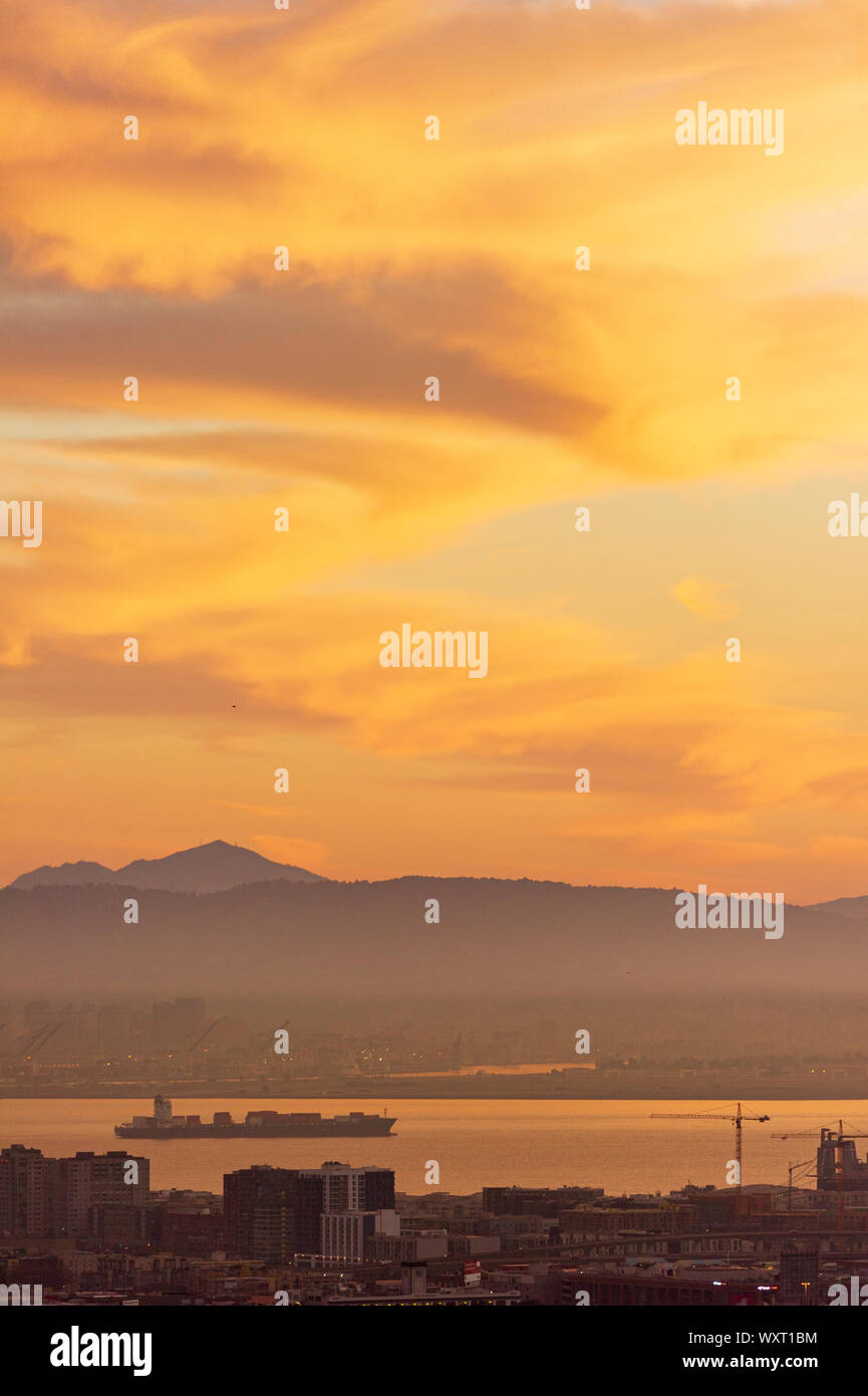 A cargo ship at sunrise moves out from the port of Oakland in the San Francisco Bay Stock Photo