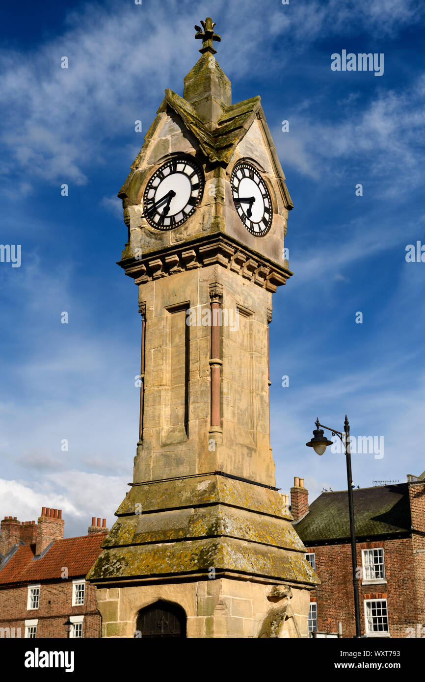 Evening light on Clock tower made of yellow Cotswold limestone with blue sky in the Town Centre of Thirsk Market town North Yorkshire England Stock Photo