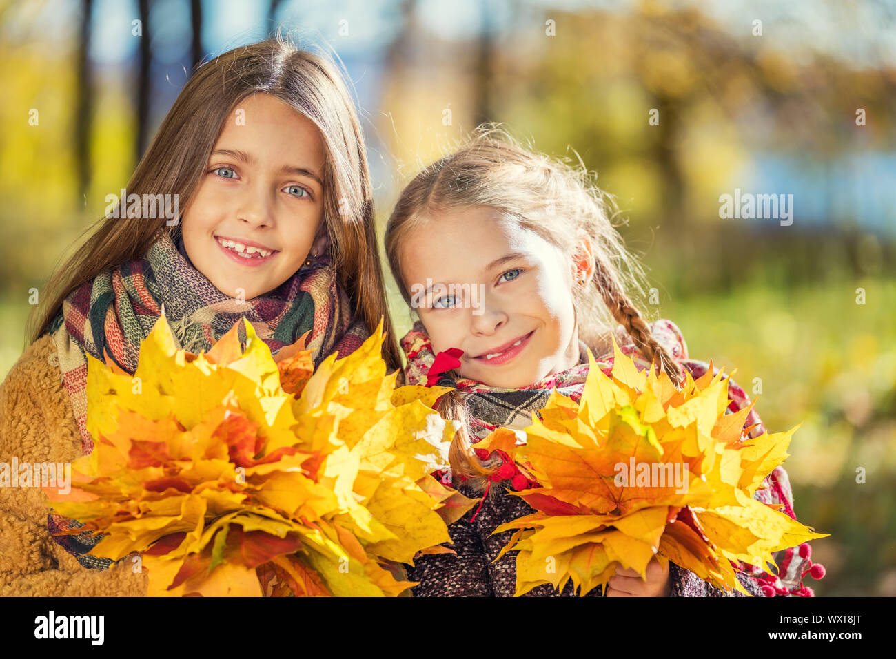 Two cute smiling 8 years old girls posing together in a park on a sunny autumn day. Stock Photo