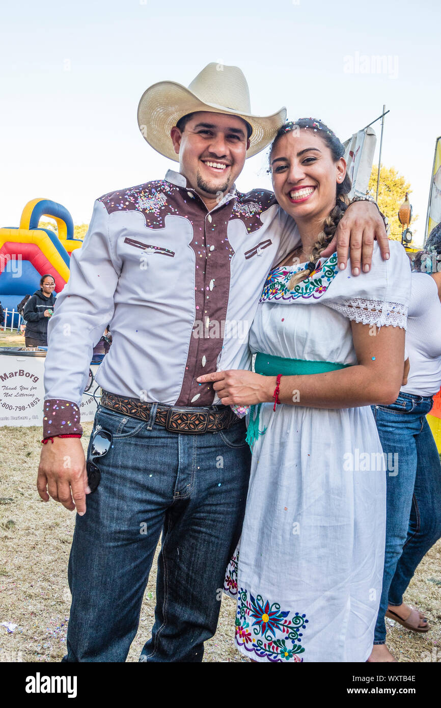 A Hispanic couple at the Mercado del Norte, part of the fiesta in Santa Barbara, California. They smile as he holds his arm around her and both of the Stock Photo