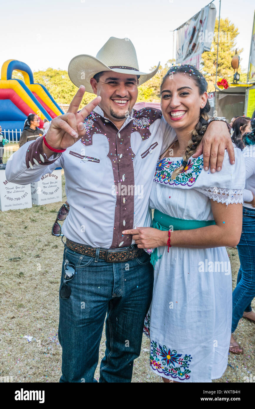 A Hispanic couple at the Mercado del Norte, part of the fiesta in Santa Barbara, California. They smile as he holds his arm around her and both of the Stock Photo