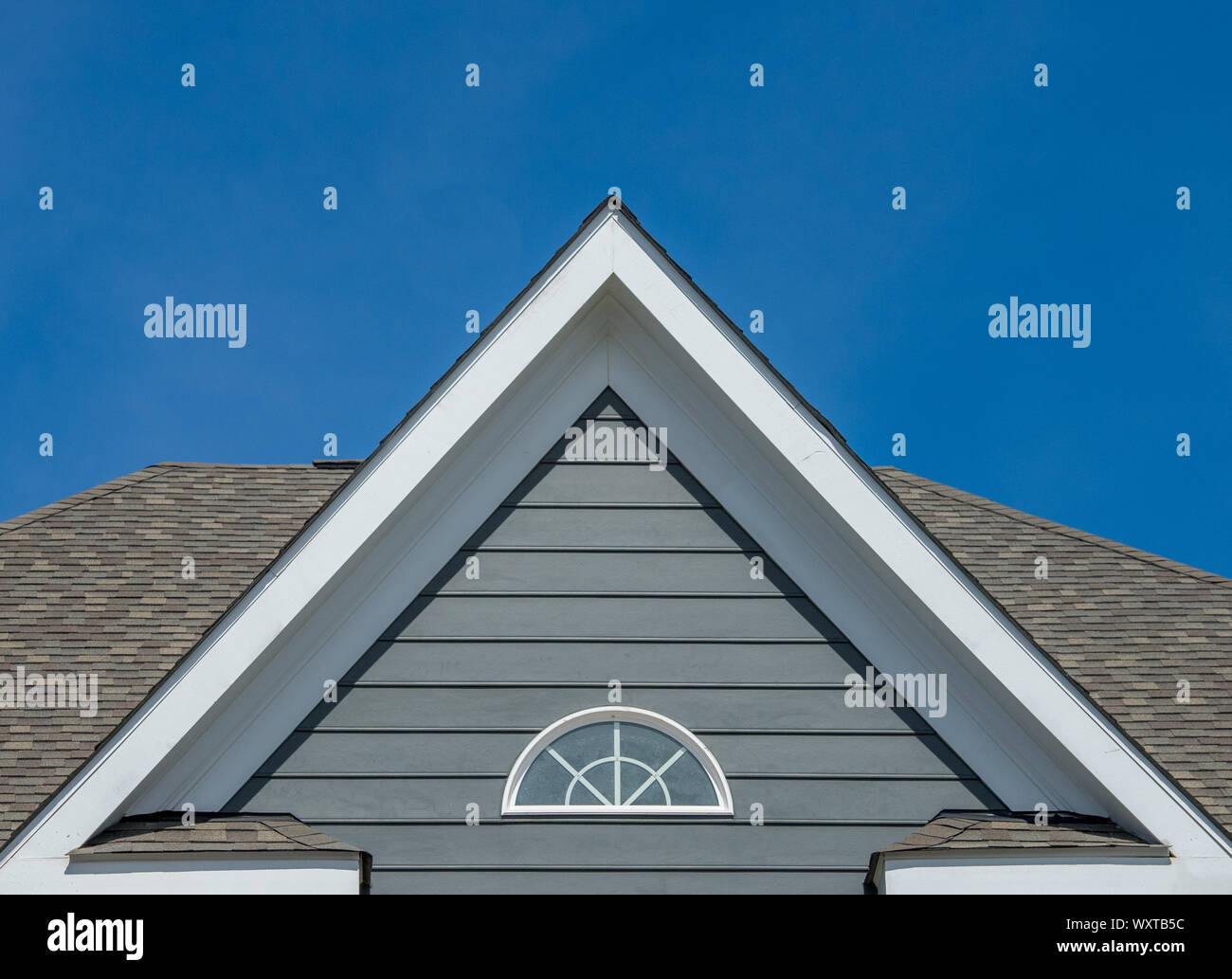 White attic window vent, gable, corbel, louver on a new construction luxury American single family home in the East Coast USA with blue sky background Stock Photo