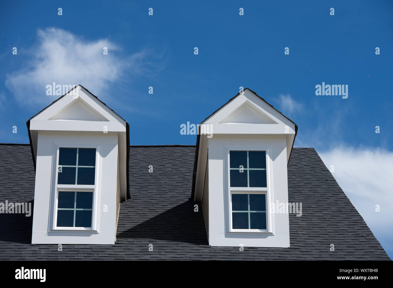 A dormer window with a gable roof blue cloudy sky background on a new construction single family home in the USA Stock Photo