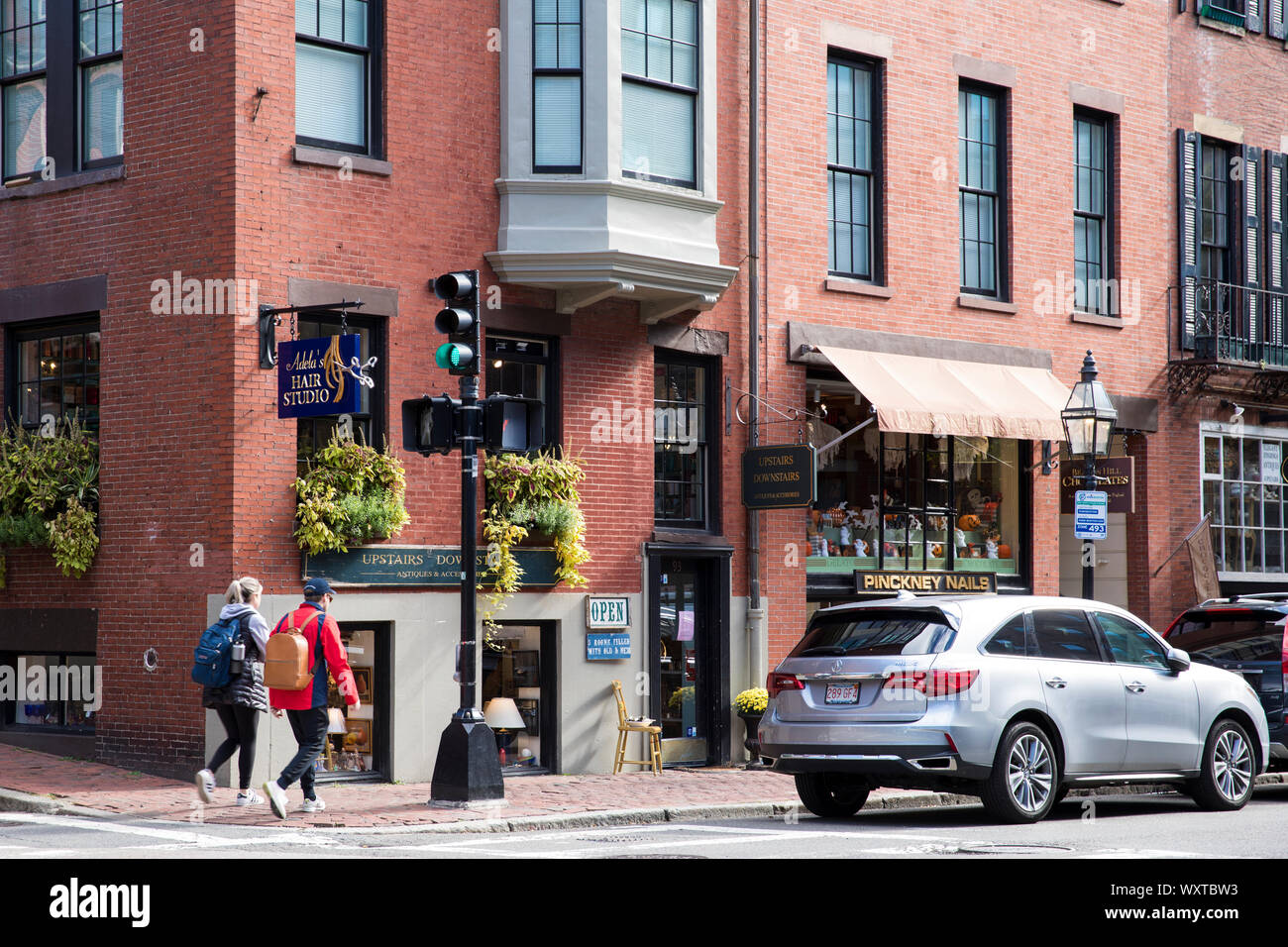 Street scene of people walking, shops, traffic and traffic lights - in historic district of Charles Street, city of Boston, USA Stock Photo