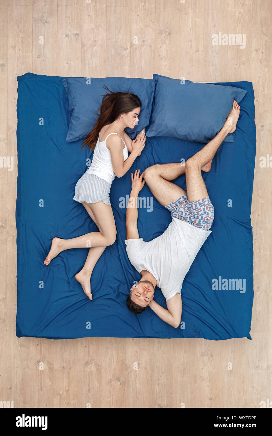 Bedtime. Young couple sleeping headtotoe on bed top view peaceful