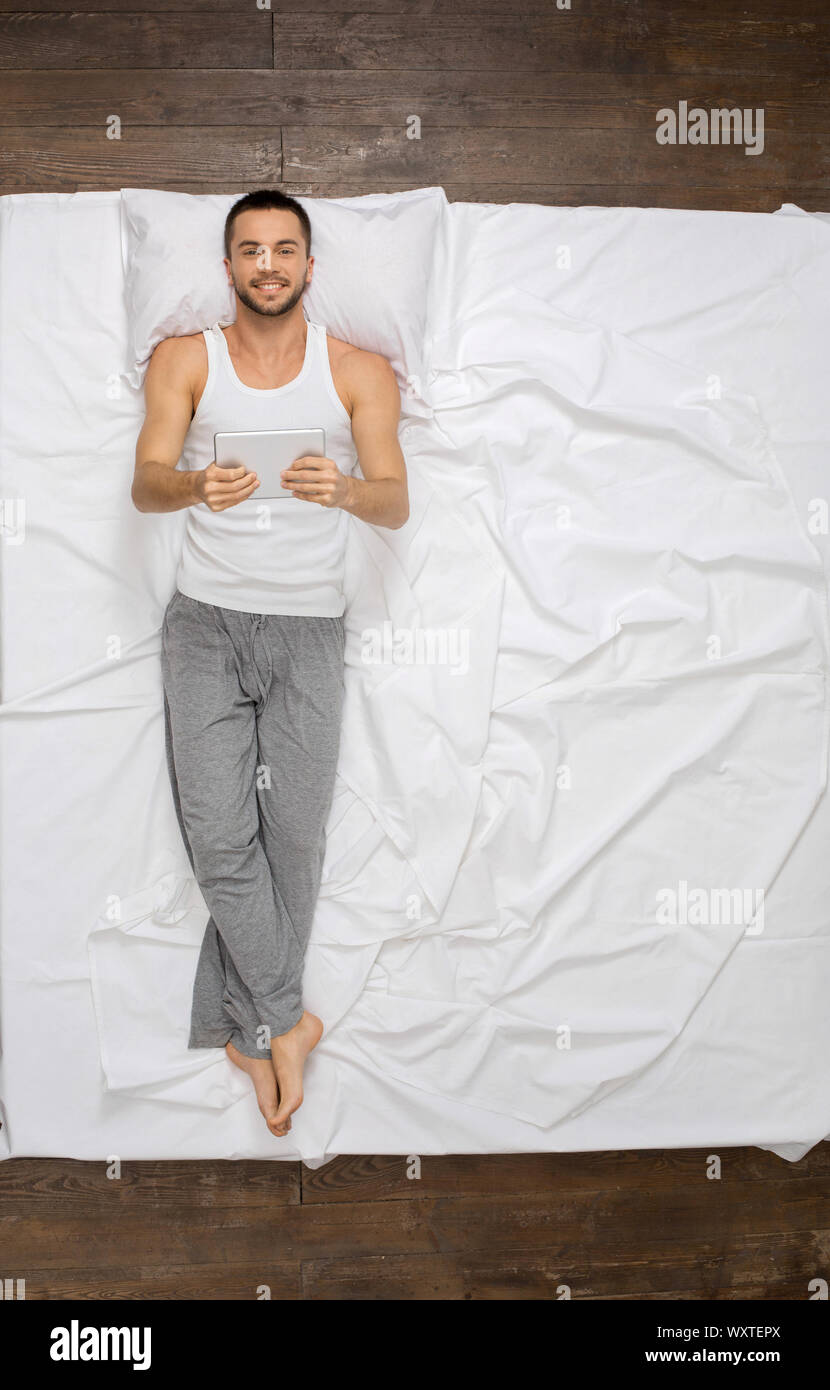Young man relaxation on the bed top view using digital tablet Stock Photo