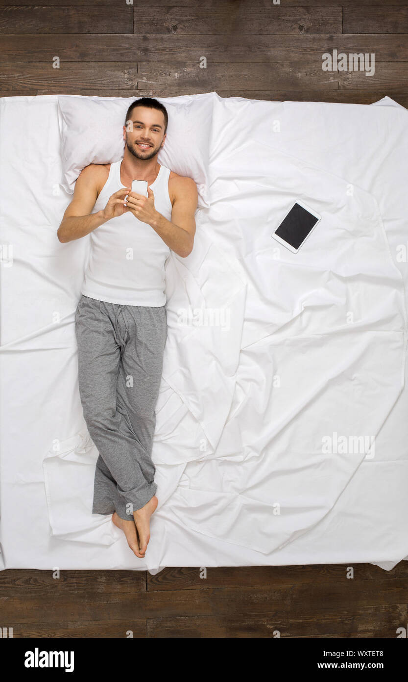 Young man relaxation on the bed top view using smartphone Stock Photo