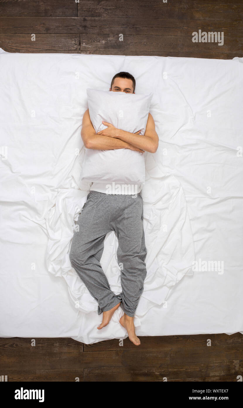 Young man relaxation on the bed top view hugging pillow Stock Photo