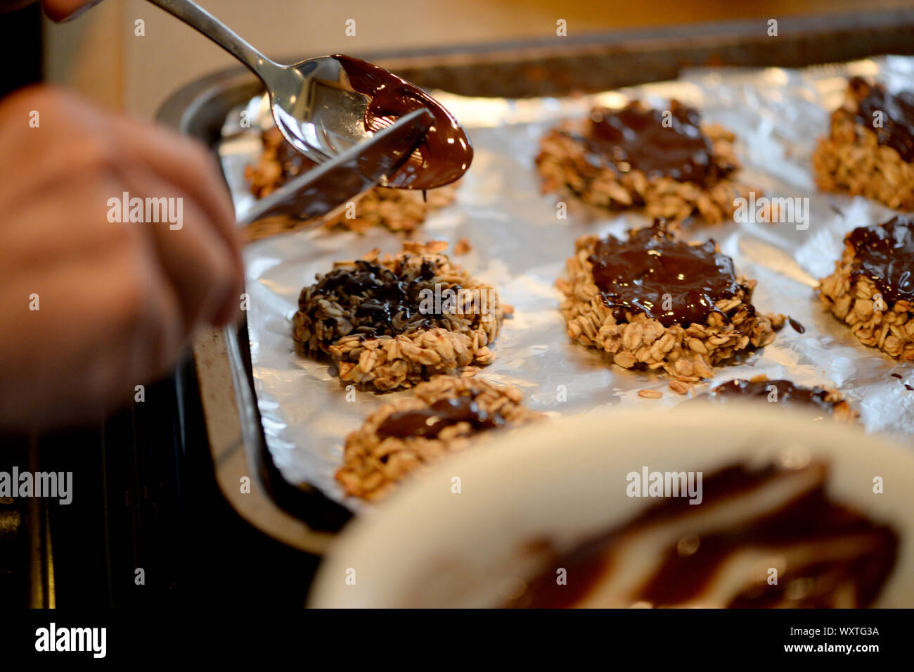 Coating the oat and banana cookies with chocolate Stock Photo