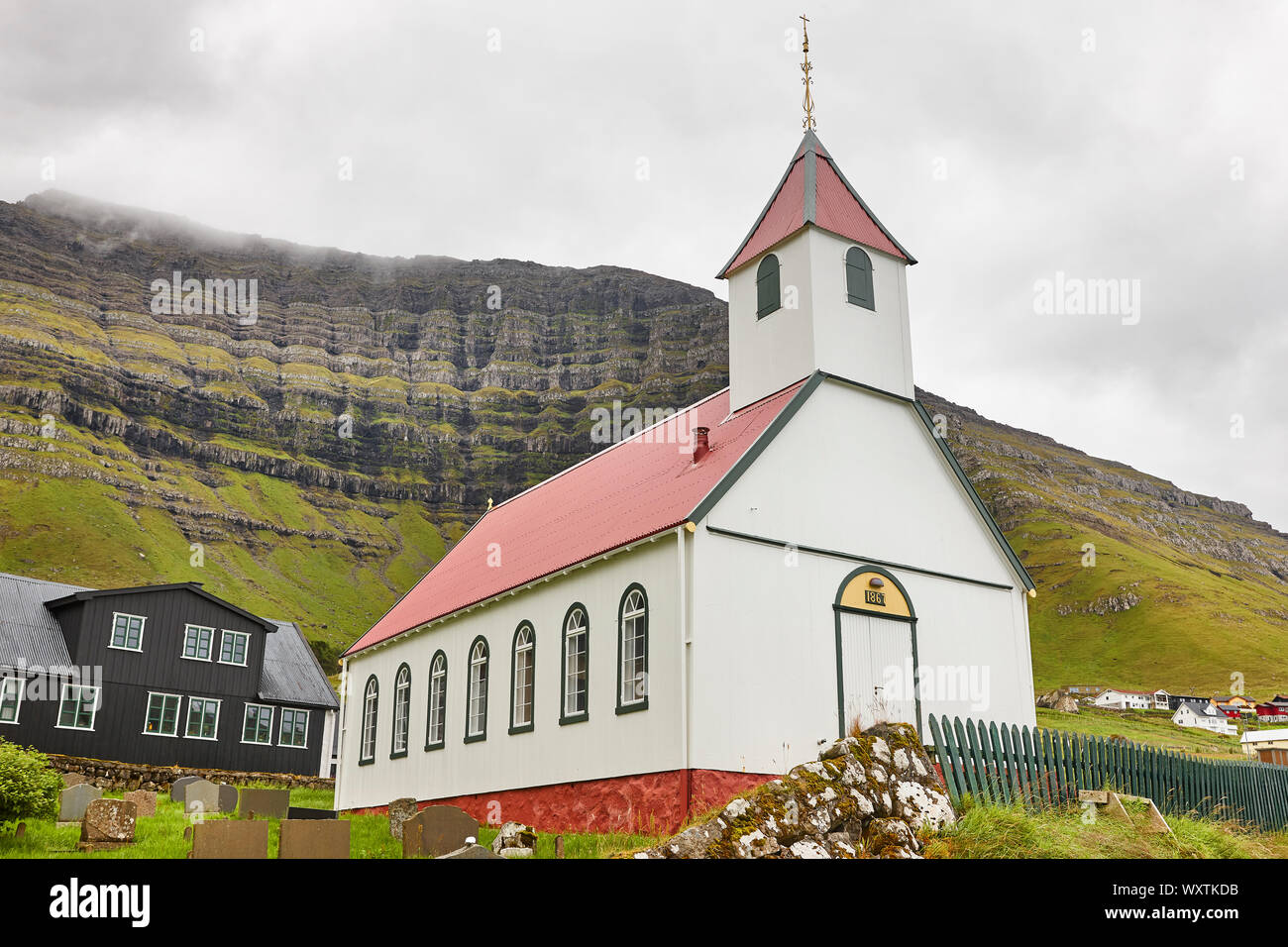 Traditional Faroe village of  Kunoy with picturesque church and mountain Stock Photo