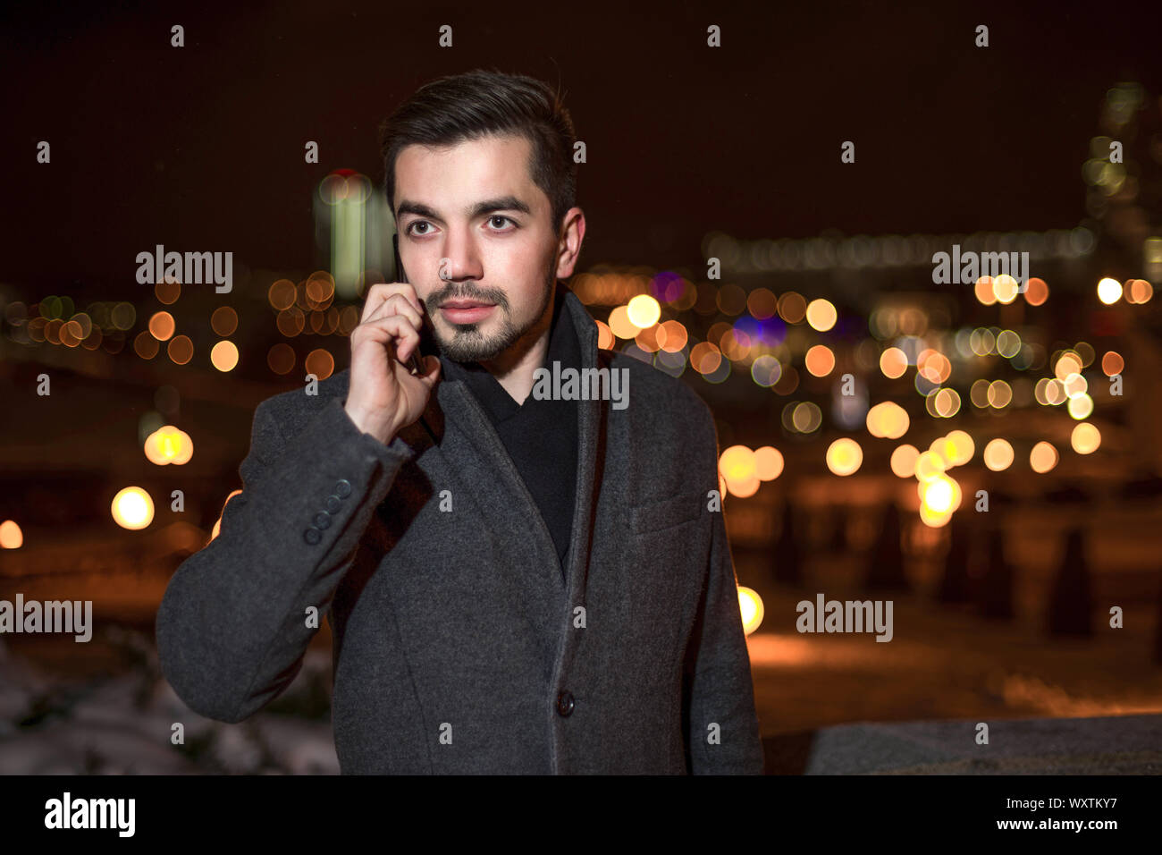 man dressed in a business style on the street in the evening talking on the phone. Stock Photo