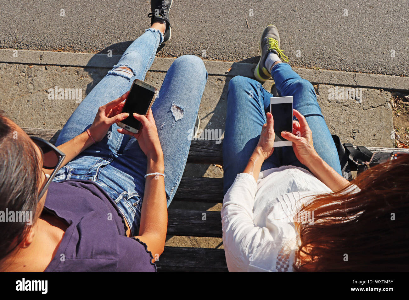 Two young girls watching smart mobile phones Stock Photo
