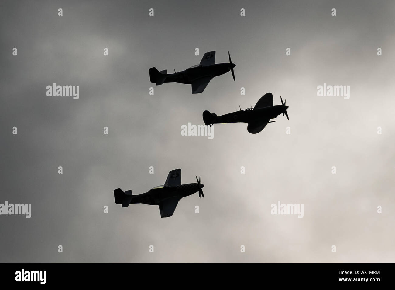 The vintage-themed Goodwood Revival. Britain’s greatest annual classic car show. Rolls Royce Merlin Spitfire Mk IX (middle) and two P51D Mustang fighter planes take to the skies starting three days of action at what was once RAF Westhampnett. UK. Stock Photo