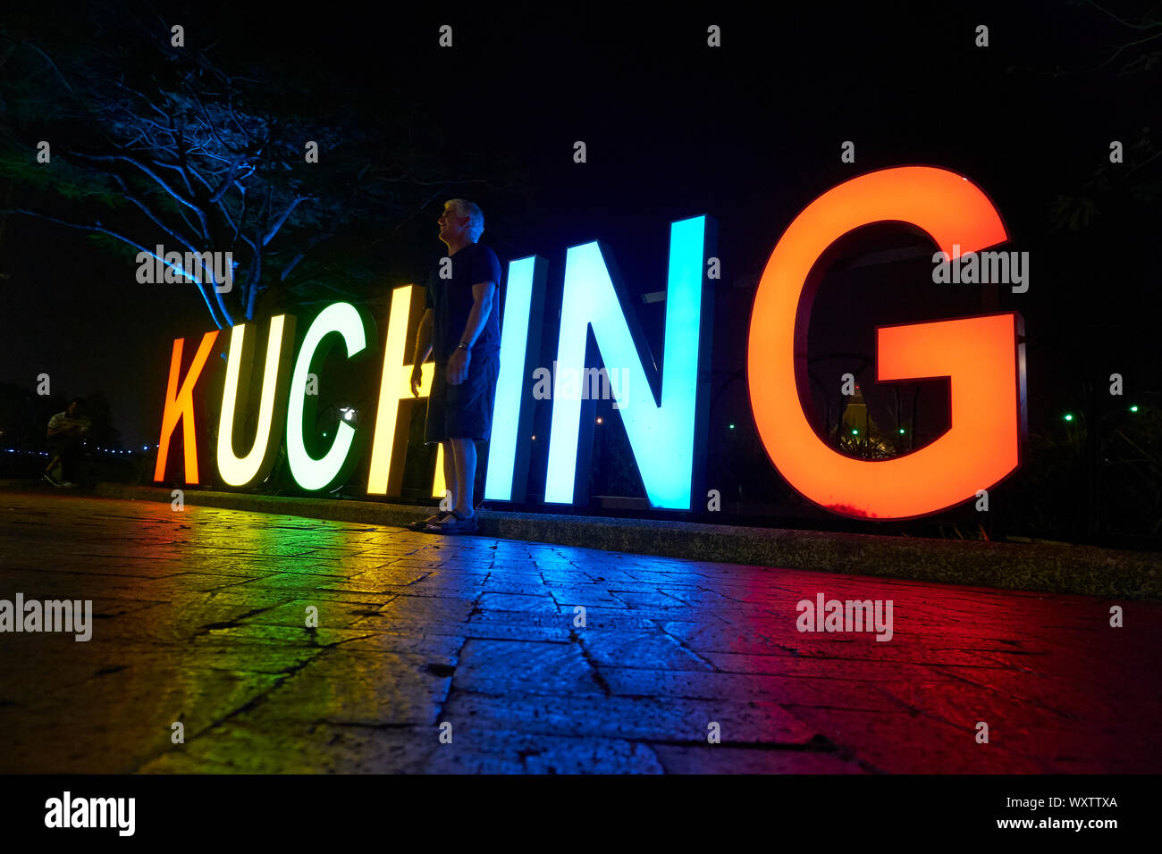Someone posing in front of the big, illumunated city of Kuching sign that is located on the riverfront promendae. In Kuching, Sarawak, Borneo, Malaysi Stock Photo
