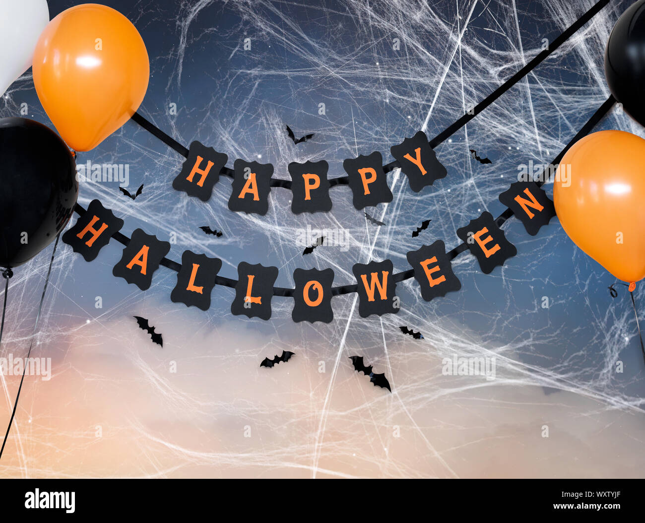 holidays, decoration and party concept - happy halloween festive paper black garland or banner with air balloons, spiderweb and bats over starry night Stock Photo