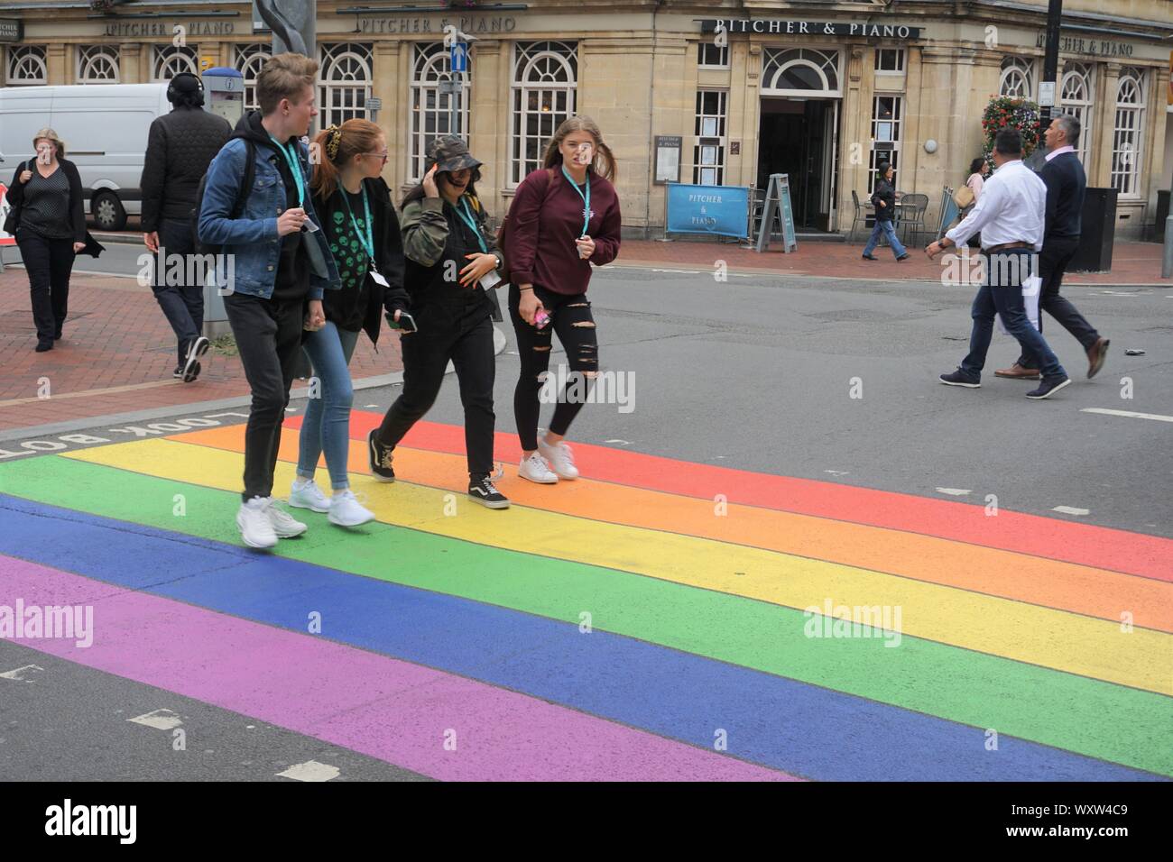 Pedestrians crossing road at a Zebra crossing painted in LGBT rainbow colours in Reading, UK Stock Photo