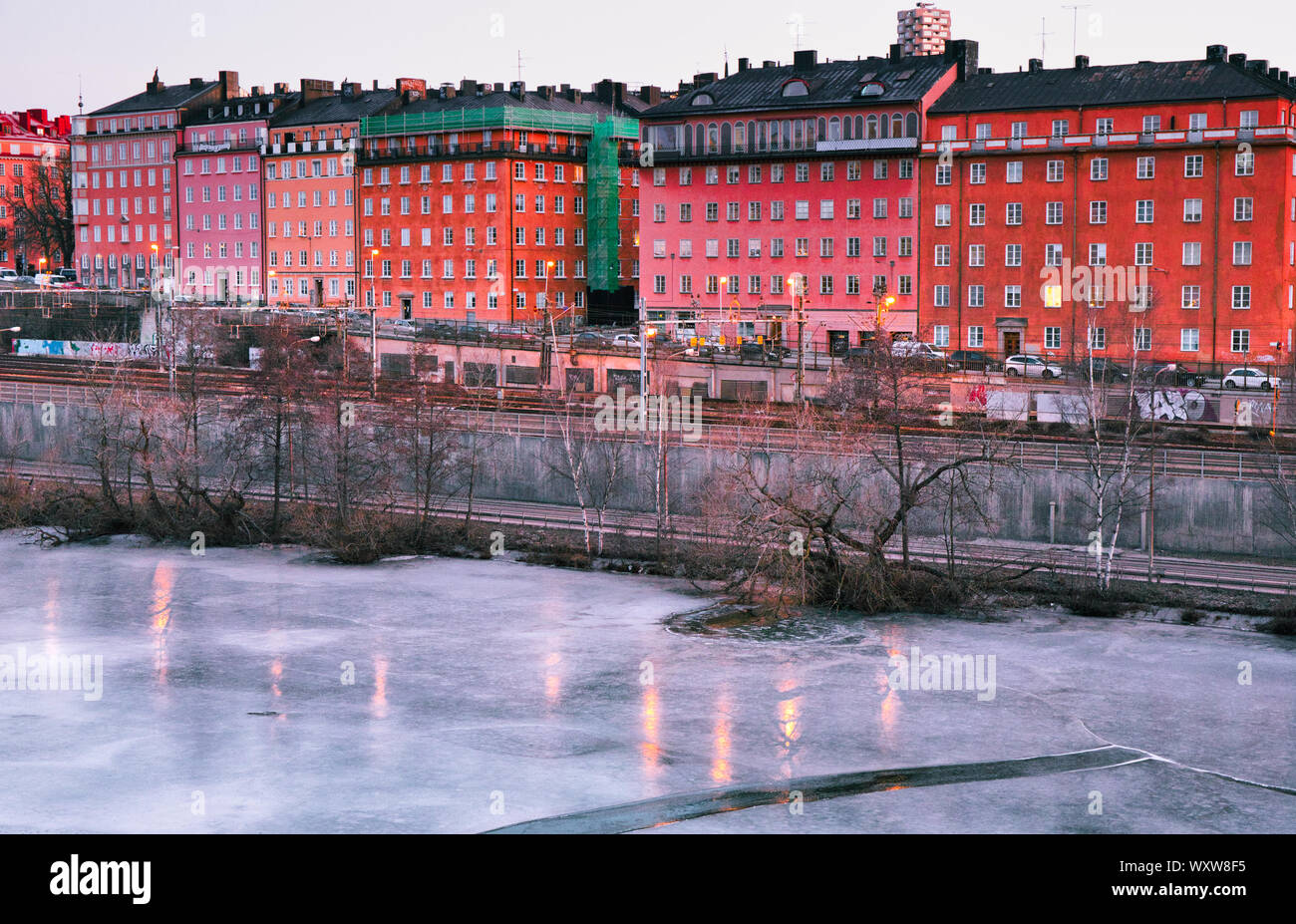 Dawn light on the frozen ice of Karlberg Lake (Karlbergssjon) with colourful facades of the Atlas district houses, Norrmalm, Stockholm, Sweden Stock Photo