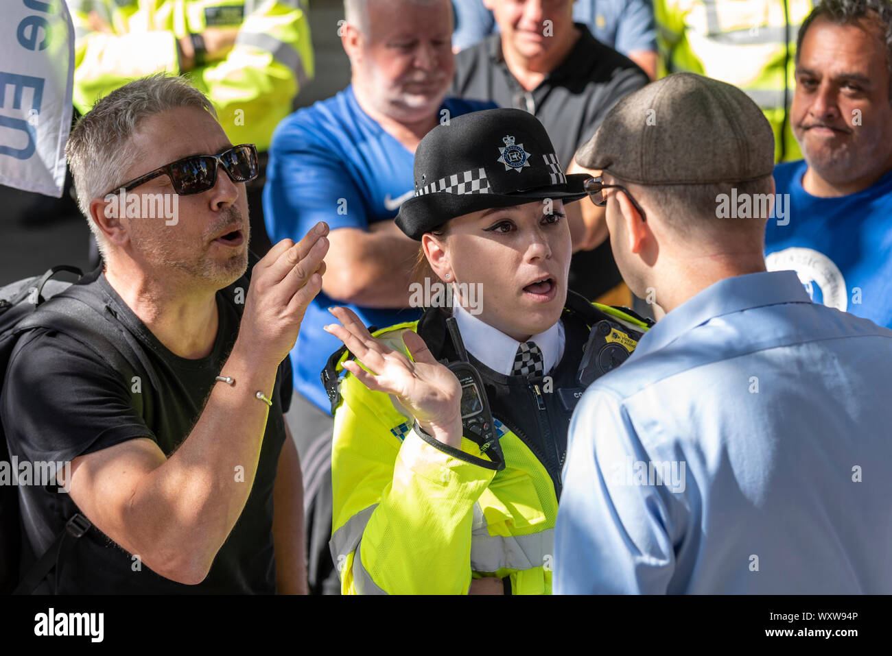 Female police officer separating opposing protesters outside the Supreme Court of the UK in Westminster, London, UK. Angry. Attractive wpc Stock Photo