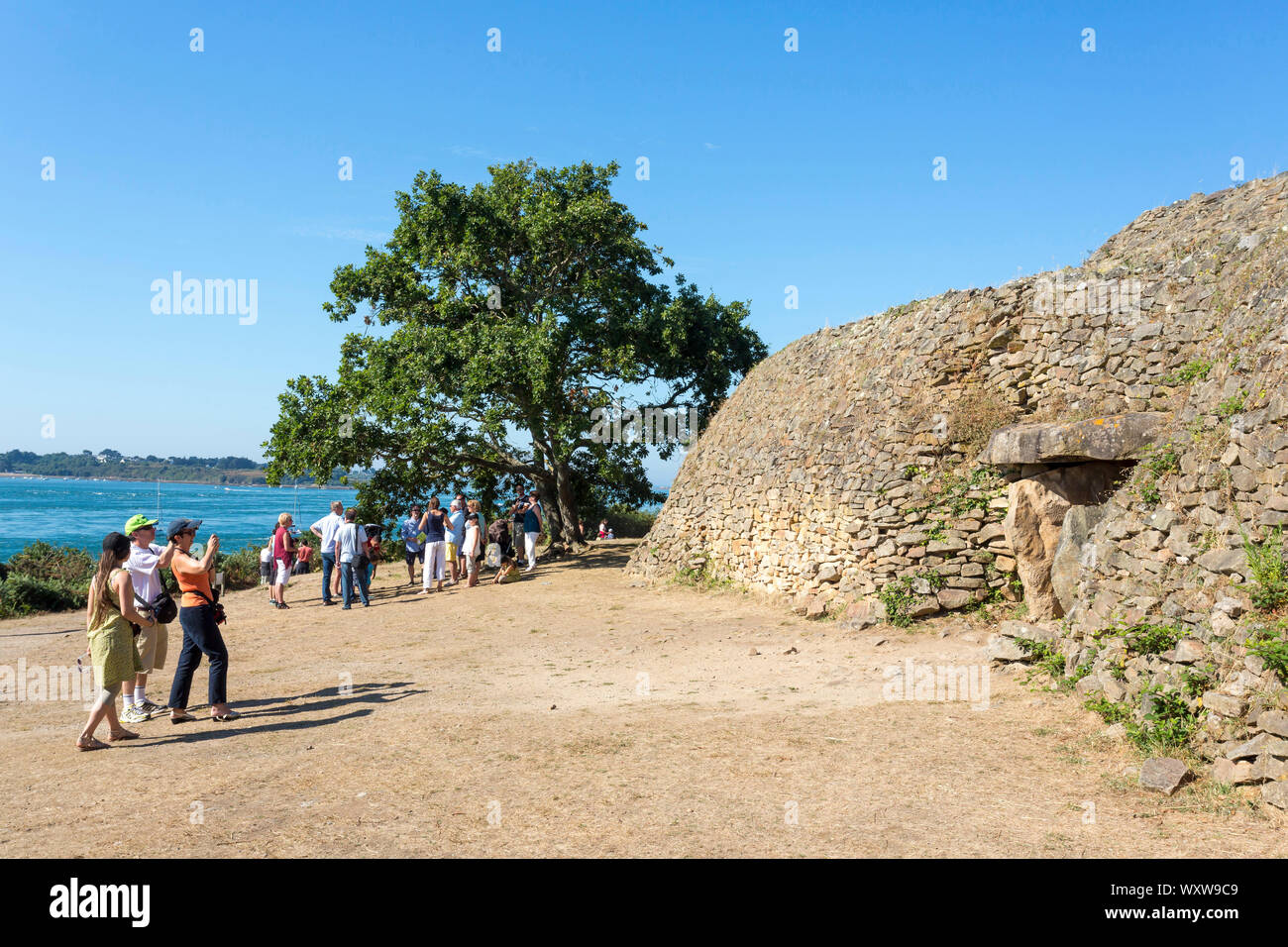 Cairn of the Island of Gavrinis in Larmor Baden in the Gulf of Morbihan (Brittany, north-western France). Group of tourists in front of the cairn for Stock Photo