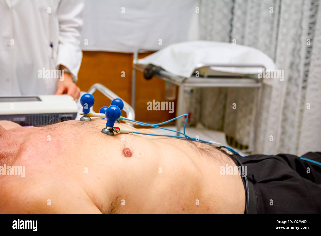 Cardiologist is attaching vacuum sensors to elder patient for recording ...