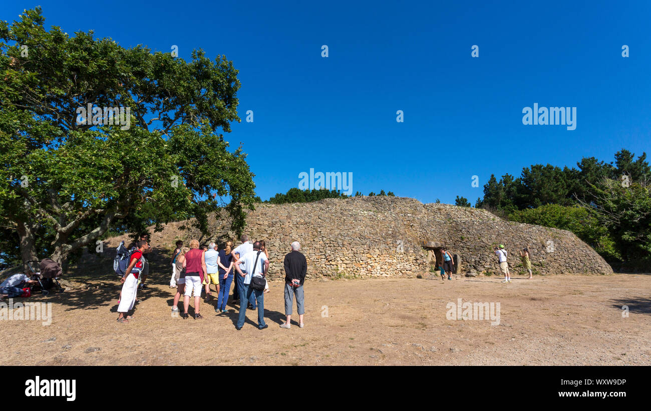 Cairn of the Island of Gavrinis in Larmor Baden in the Gulf of Morbihan (Brittany, north-western France). Group of tourists in front of the cairn for Stock Photo