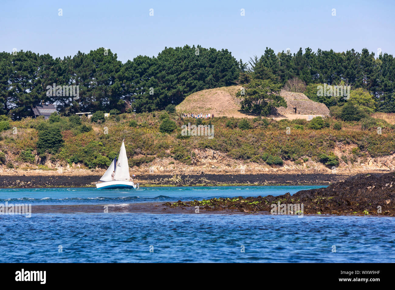 Cairn of the Island of Gavrinis in Larmor Baden in the Gulf of Morbihan (Brittany, north-western France). Sailboat in front of the island Stock Photo