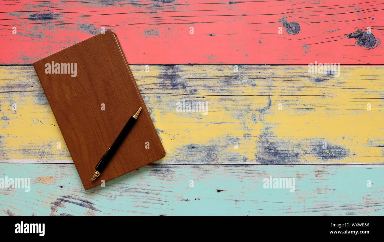 Note book with wooden cover, and a black ball pen on top of it. With empty space on the right. Stock Photo