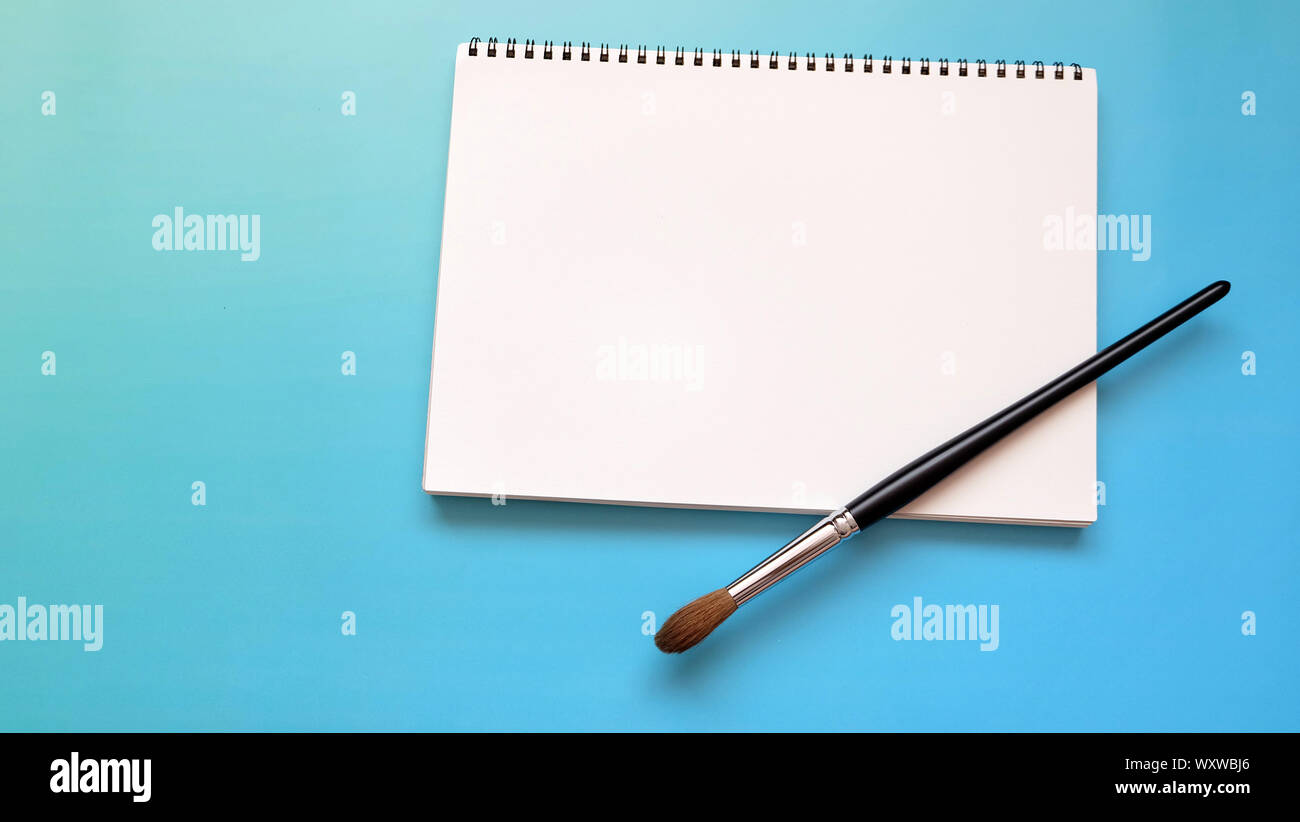 https://c8.alamy.com/comp/WXWBJ6/white-blank-sketch-pad-with-a-large-water-color-brush-on-a-vibrant-blue-background-WXWBJ6.jpg