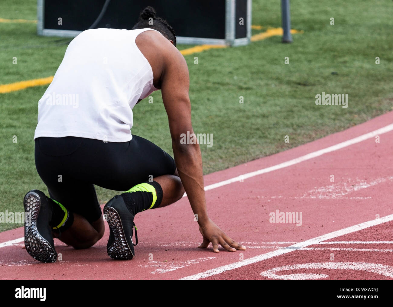 A high school sprinter is ready to start his race while he is in the on your mark position waiting to race. Stock Photo