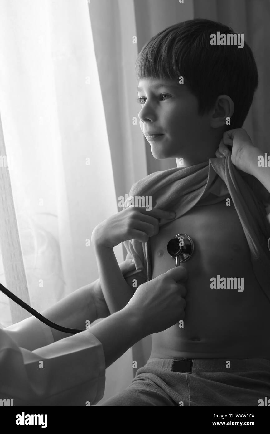 Black and white portrait of a boy examined with a stethoscope by a pediatrician doctor Stock Photo