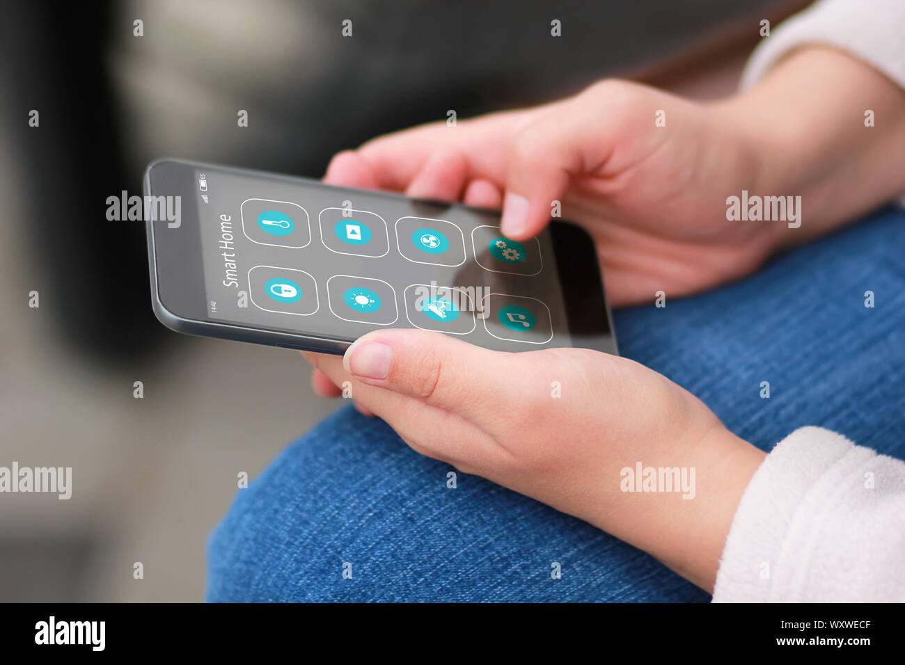 Closeup of woman's hands with black smartphone and Smart home application icons interface design. House automation concept. Stock Photo