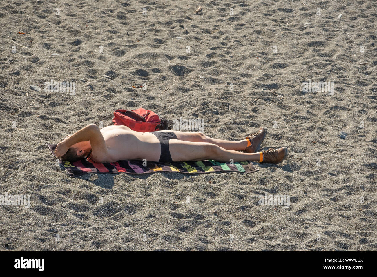 Aberystwyth Wales UK, Wednesday 18th September 2019  UK Weather: A man sunbathing on the beach,  making the most of a day of clear blue skies and warm September sunshine at the seaside in Aberystwyth on the Cardigan Bay coast, west Wales, as a high pressure system dominates the weather over the souther half of the UK. Photo credit Keith Morris / Alamy Live News Stock Photo