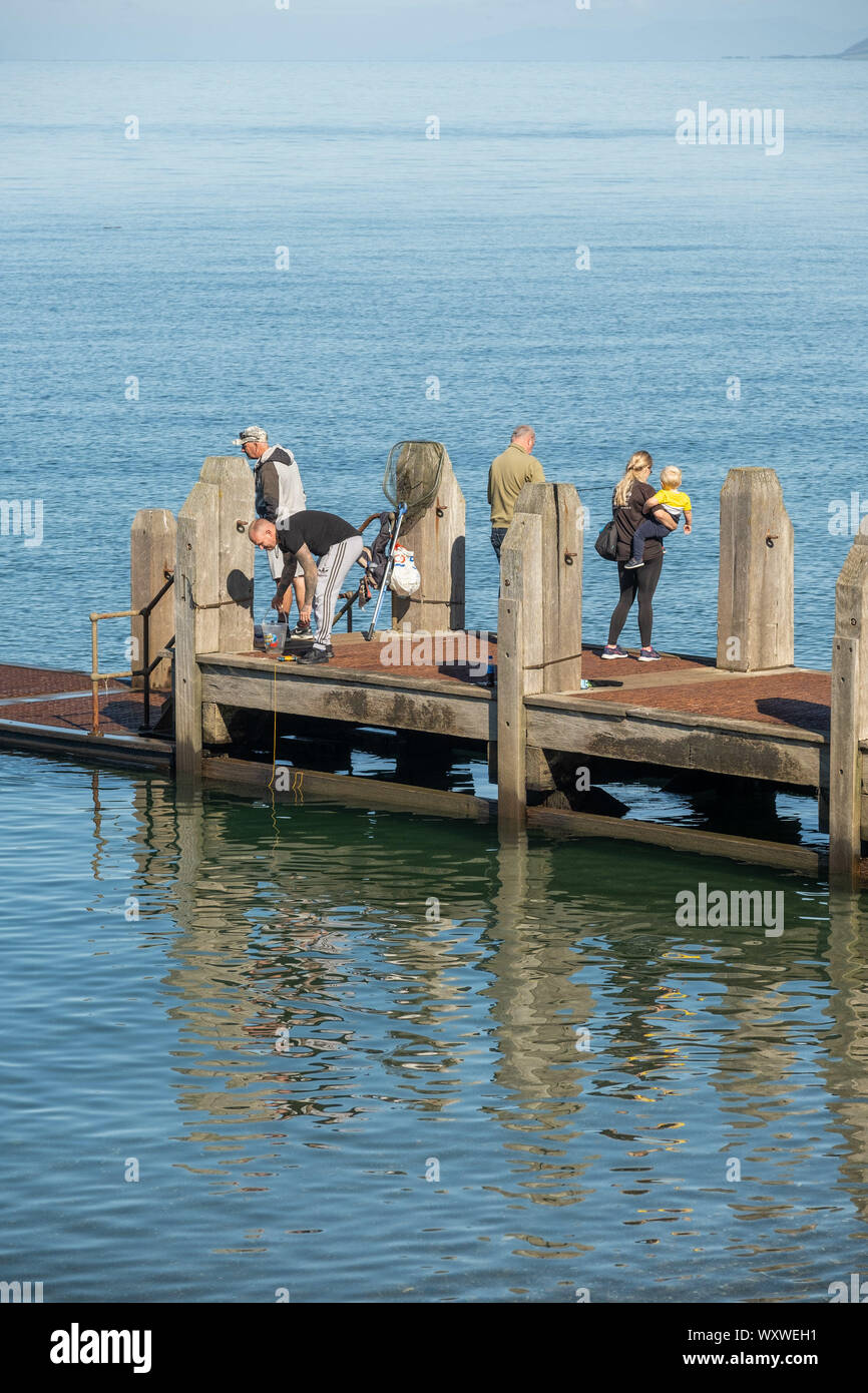 Aberystwyth Wales UK, Wednesday 18th September 2019  UK Weather: People on the wooden jetty making the most of a day of clear blue skies and warm September sunshine at the seaside in Aberystwyth on the Cardigan Bay coast, west Wales, as a high pressure system dominates the weather over the souther half of the UK. Photo credit Keith Morris / Alamy Live News Stock Photo