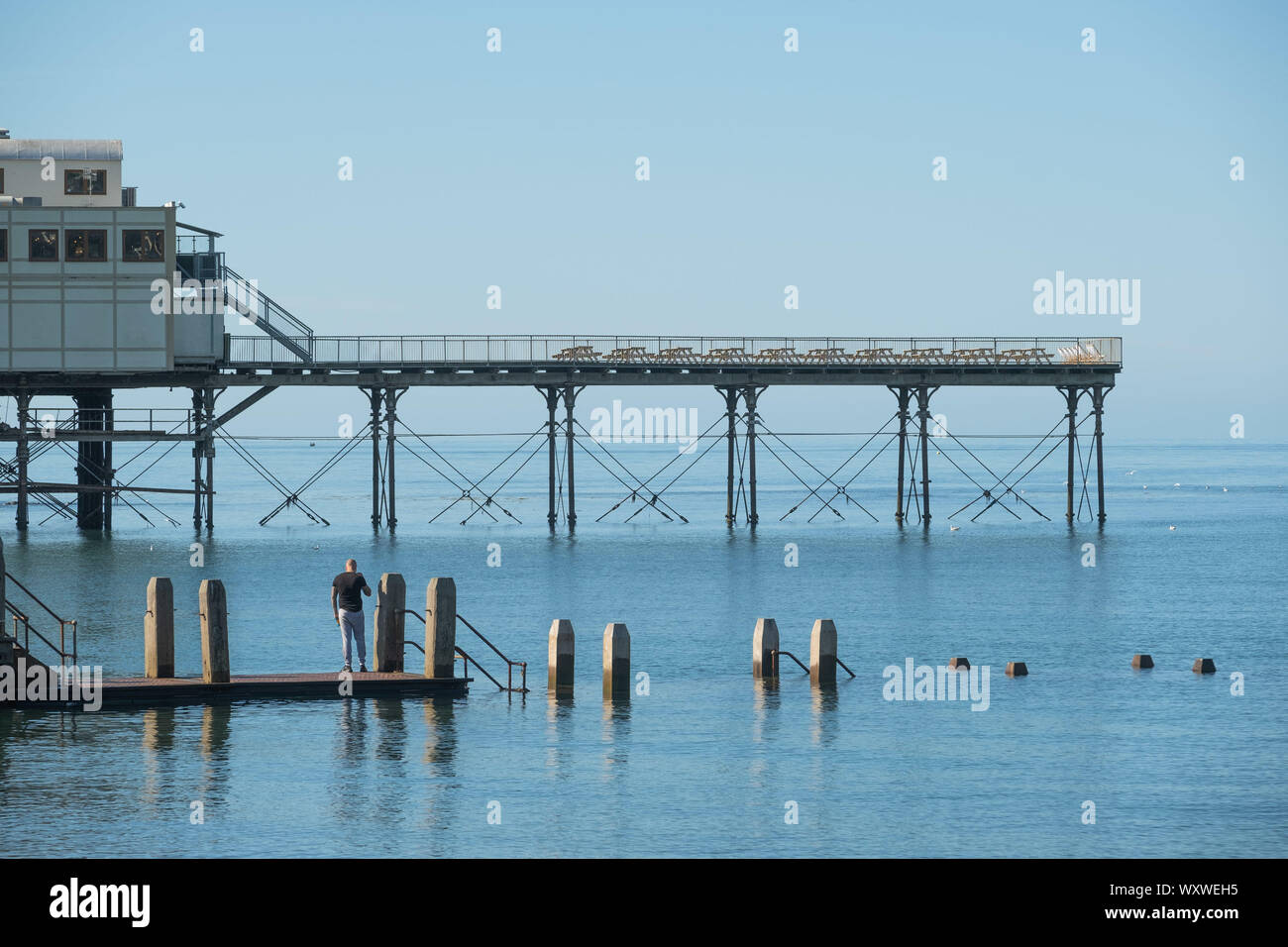 Aberystwyth Wales UK, Wednesday 18th September 2019  UK Weather: People on the wooden jetty making the most of a day of clear blue skies and warm September sunshine at the seaside in Aberystwyth on the Cardigan Bay coast, west Wales, as a high pressure system dominates the weather over the souther half of the UK. Photo credit Keith Morris / Alamy Live News Stock Photo