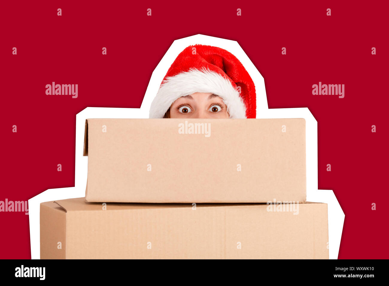 Surprised Woman in christmas hat holding christmas present in front of ...