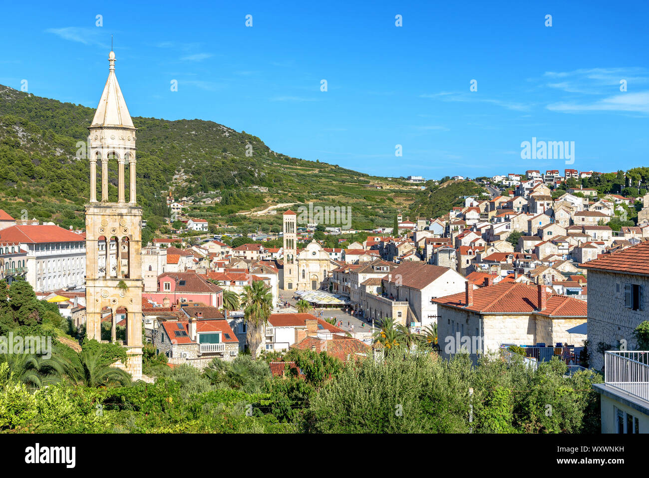 The bell tower of the former St. Mark's Church (Crkva Sv. Marka) in Hvar, Croatia with Trg Sv. Stjepana and the town in the background Stock Photo