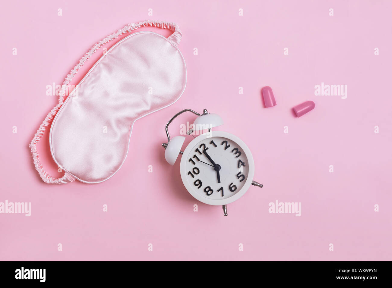 Sleeping mask, alarm clock and earplugs pn patel pink background, Stock Photo